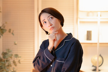 悩むパジャマ姿の女性