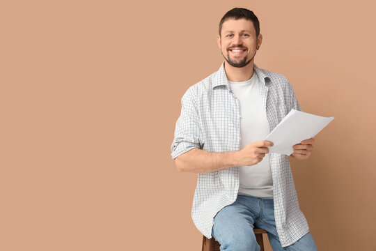 Male actor with film script on beige background