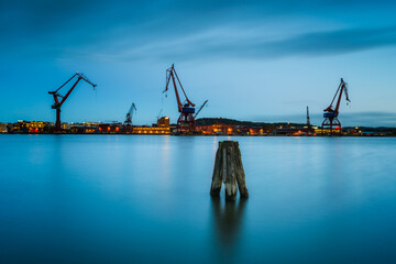 Fototapeta premium Cranes silhouette against the dusky harbor skyline of Gothenburg at twilight