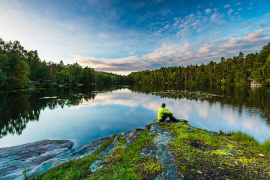 Calm man reflecting by a serene lake near Gothenburg during a peaceful evening