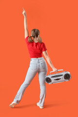 Young woman with boombox dancing on orange background, back view