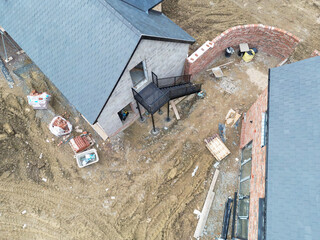 Interesting drone view of an under construction detached garage showing a new exterior metal staircase which leads to above garage room space. The detached house is also in view.
