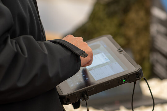 A man in a dark jacket uses a secure tablet to control military systems.