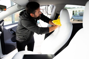 Adult male cleaning car interior with yellow cloth