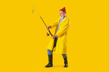 Senior man with fishing rod on yellow background