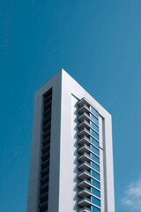 Clean minimalist city skyscraper against bright blue sky in modern urban landscape