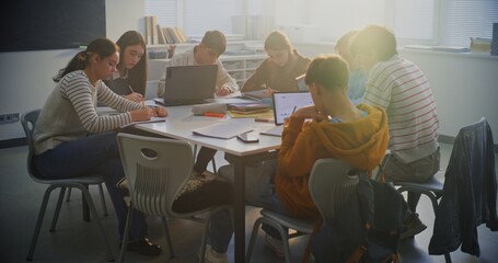 Young Pupils Deeply Concentrated Around Shared Table, Working on Group Project Using Mix of Laptops, Tablets, Notebooks. Concept Digital Learning, Teamwork in Modern Learning Environment. Dolly Shot.