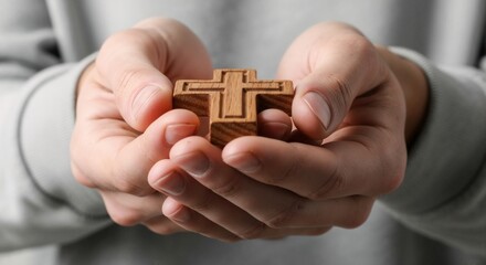 Fototapeta premium Hands gently cradling a wooden cross, symbolizing faith and spiritual devotion.