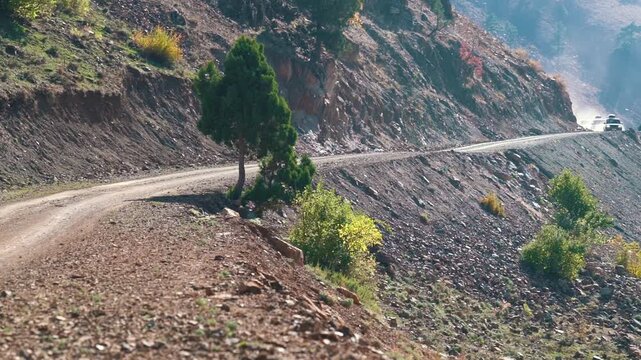 Cars leave from behind the mountain and rush along the serpentine. 