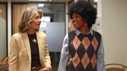 Diverse female colleagues discussing project on tablet computer in office hallway - Powered by Adobe