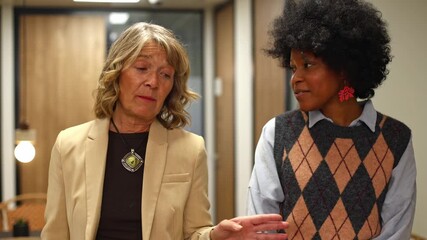 Mature businesswoman mentoring young colleague in office corridor - Powered by Adobe