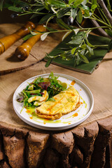 Freshly made omelette served with a vibrant salad on rustic wooden table