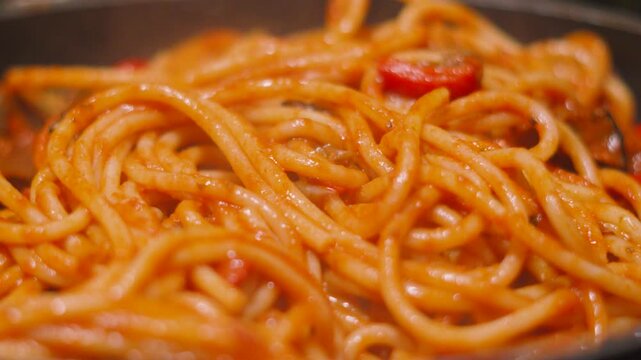 Italian Tomato Based Pasta Bucatini Spaghetti with Aubergine Egg Plant and Peppers in Pan. Delcious Cooking Close Up Food Clip.