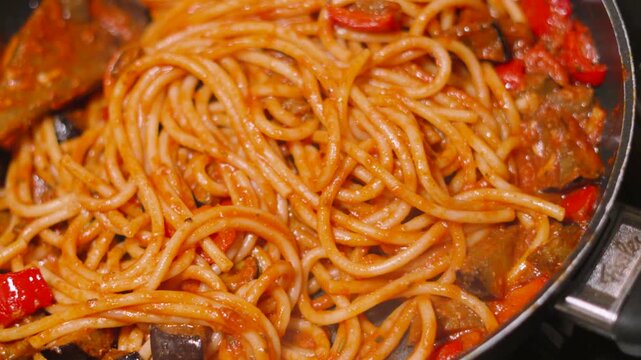 Top View of Italian Tomato Based Pasta Bucatini Spaghetti with Aubergine Egg Plant and Peppers. Delcious Cooking Close Up Food Clip.