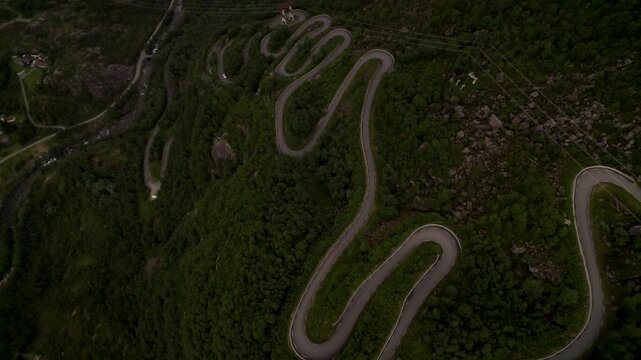 Aerial view of a winding road snaking through a verdant mountain landscape, creating a striking contrast between nature and infrastructure, Lysebotn, Rogaland, Norway.