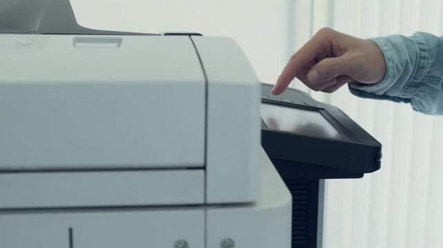 Close-up of person operating modern office printer or copier by pressing touchscreen panel. Office workflow, technology, document management in professional environment