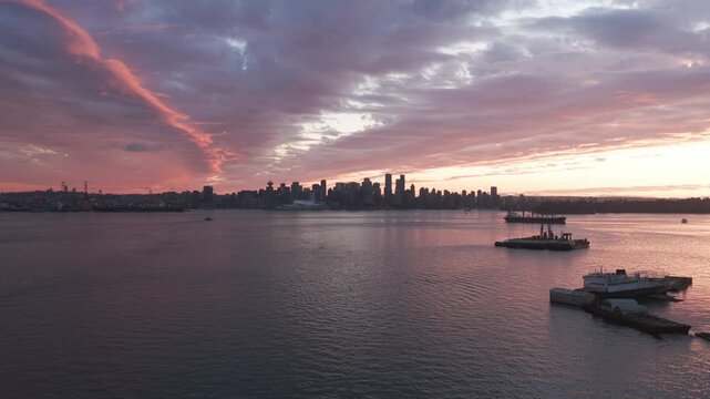 Aerial wide rising shot of downtown Vancouver during magic hour from the shore of North Vancouver, British Columbia, Canada. 4K