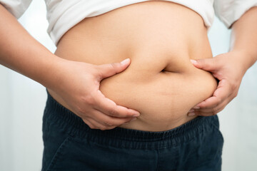 Asian woman use hand to squeeze fat belly big size overweight and obesity.