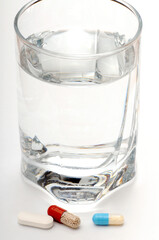 Glass of water with Three Different Pills in Front – Vertical Composition