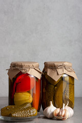 Two glass jars filled with assorted pickled vegetables, sealed with kraft paper and twine. Copy space