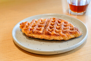 A crispy fish shaped waffle served on a light gray ceramic plate over a wooden table in natural light with a glass of single origin coffee. Perfect for restaurant, homemade bakery, or breakfast menu