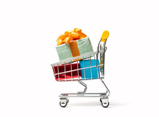 Mini shopping cart filled with bright gift boxes tied with ribbons on a white isolated background. Concept of online shopping, holiday sales, presents, and festive discounts.