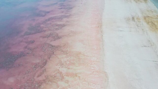 Aerial view of the striking contrast between the pink hues of Tuz Lake and the adjacent white salt flats, creating an otherworldly landscape, Tuz, Ankara, Turkiye.