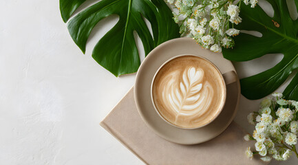 A cup of latte art coffee against a backdrop of green leaves