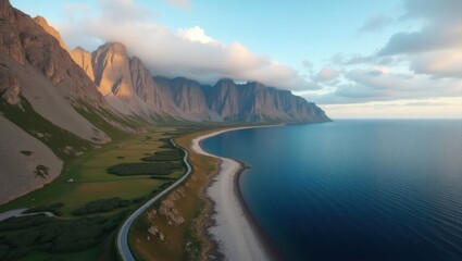 Aerial view of a winding coastal road alongside a dramatic mountain range meeting the blue ocean