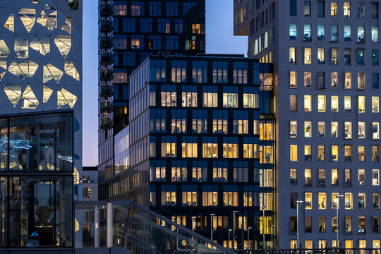 Modern architecture skyline with glass facade buildings illuminated at night in the Barcode district of Oslo, showcasing urban light reflections and contemporary city design atmosphere