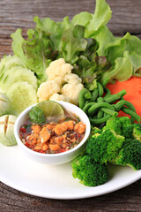 Spicy Crab Roe Relish Paste serve with Mixed fresh vegetables on vintage wood background