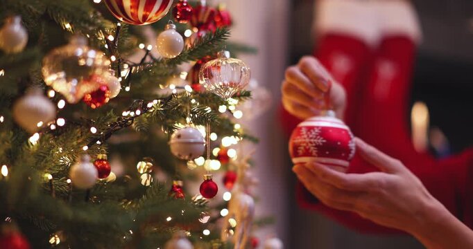 A woman's hands hang a ball on a Christmas tree. Holiday decor. Smooth camera movement