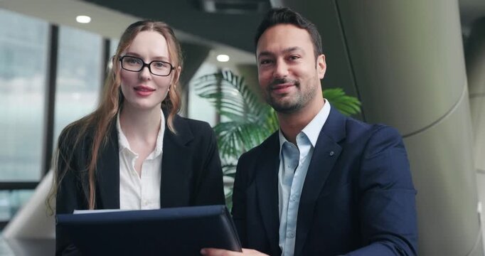Smiling business partners celebrating success, look over to explain to colleague or client
