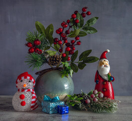 A branch with red berries and a pine branch with cones. Gift packages. Festive mood. Waiting for a Christmas miracle.