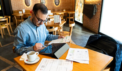 Man reviewing financial statements in a cafe