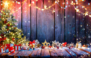 Christmas Tree With Gift Boxes On Rustic Wooden Table With Garland And Decorations - Abstract Defocused Lights