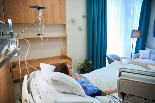 Patient lying in hospital bed undergoing intravenous therapy