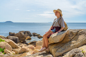 Woman in hat is sitting on a rock and dreaming
