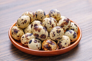 Closeup view of quail eggs in wooden plate on table