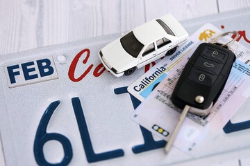 Remote control car keys on California license plate with driver license. Concept of driving in...