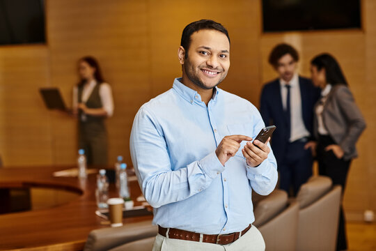 Engaging team member using smartphone in modern office setting during business meeting