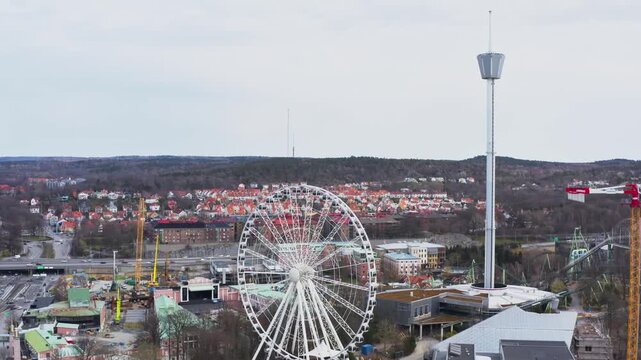 Aerial view of the towering AtmosFear and the grand Ferris wheel at Liseberg, contrasting with the red rooftops, Gothenburg, Vastra Gotaland County, Sweden.