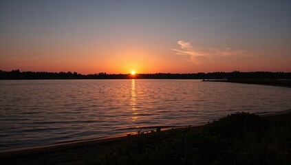 Obraz premium Sunset over the lake during evening hours, reflecting seasonal change