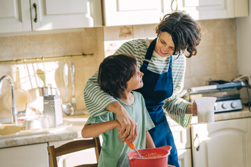 Mother and son cooking pancakes together in home kitchen