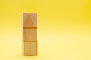 Stake of wooden cubes on yellow background with customizable space for text or ideas.