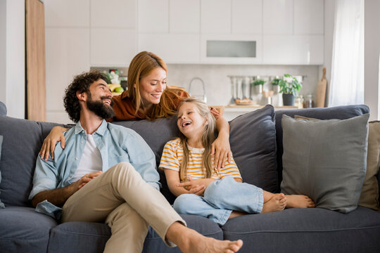 Family laughing together while hugging on living room couch