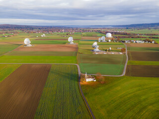 Raisting, Germany - 11 November 2025: Aerial view of the gleaming satellite dishes punctuate the landscape, standing as silent sentinels amid the patchwork quilt of autumnal fields.