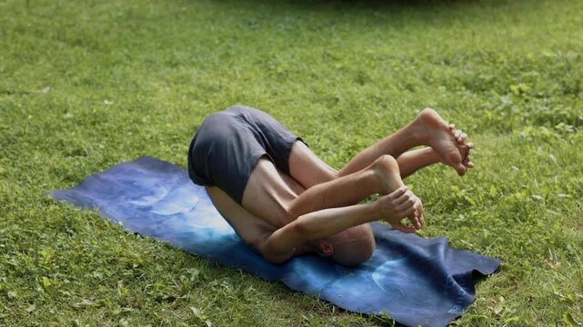 caucasian man restorative yogi practicing supine stretches in park
