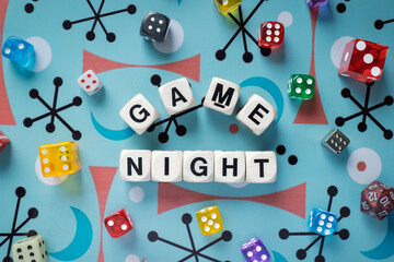GAME NIGHT spelt using wooden word dice with vibrant dice around set over a playful retro board - perfect for promoting game events or fun family gatherings.