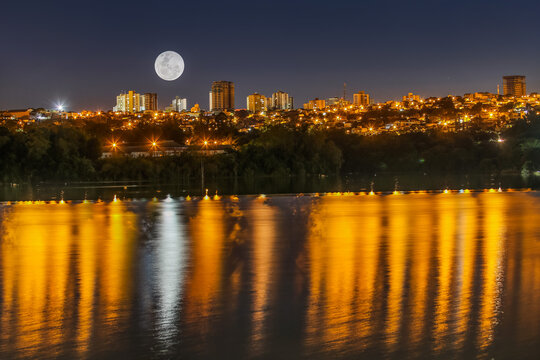 Full Moon Over City Skyline at Night with Water Reflections - Powered by Adobe